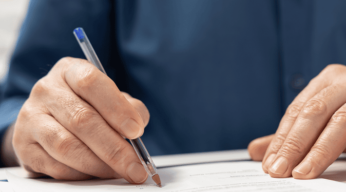 Close up of hands signing real estate and business legal paperwork