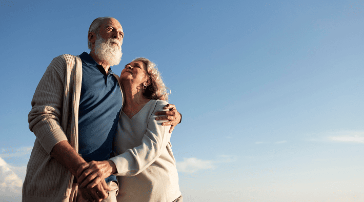 Happy senior couple standing outdoors representing retirement and estate planning