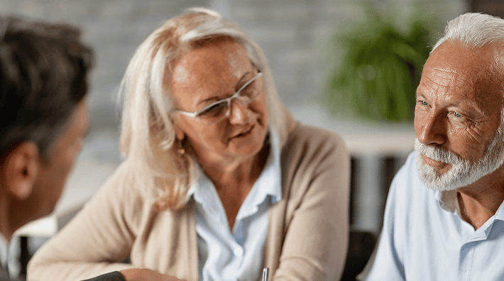 Senior couple smiling while consulting with their lawyer about future planning
