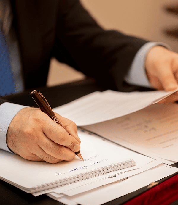 Close up of a client's hand signing a legal contract with a pen